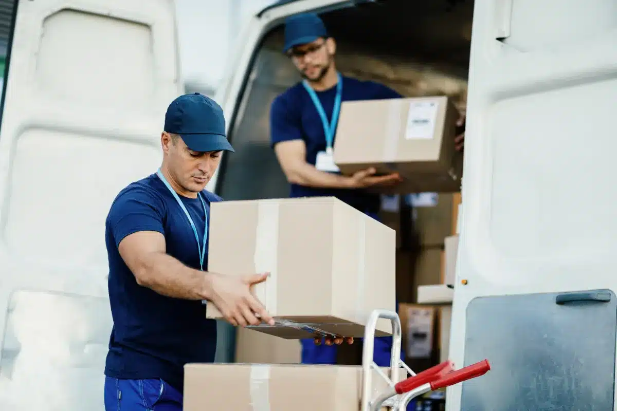 dos jóvenes descargando paquetes de una furgoneta